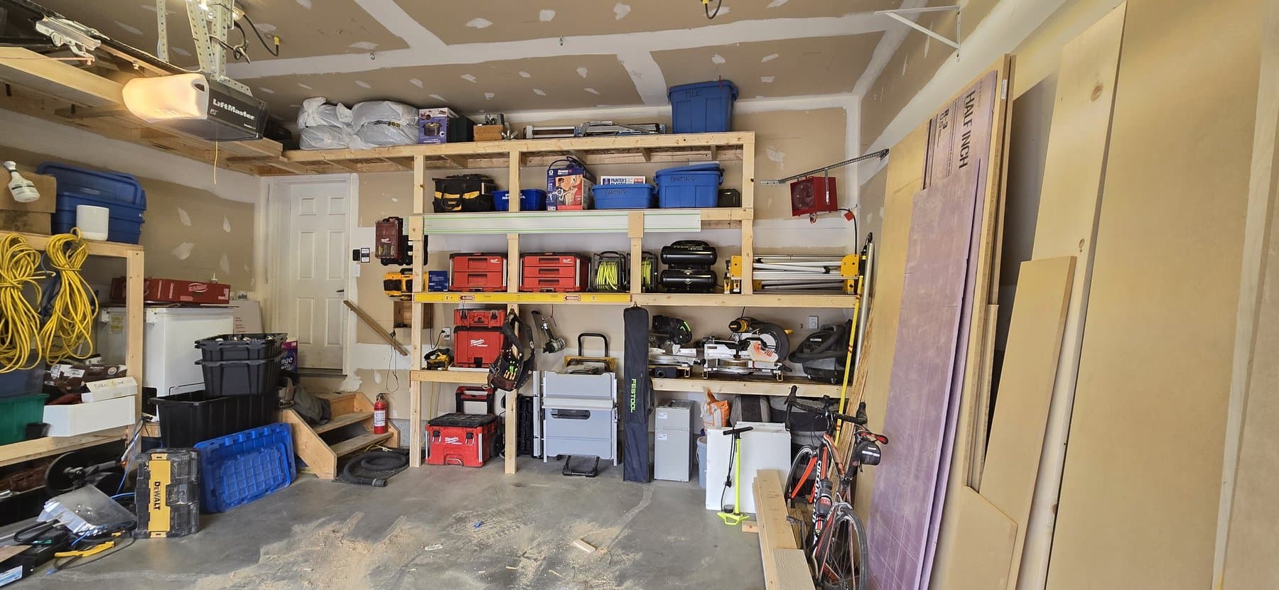 Organized shop shelving with cases of tools and sheet stock