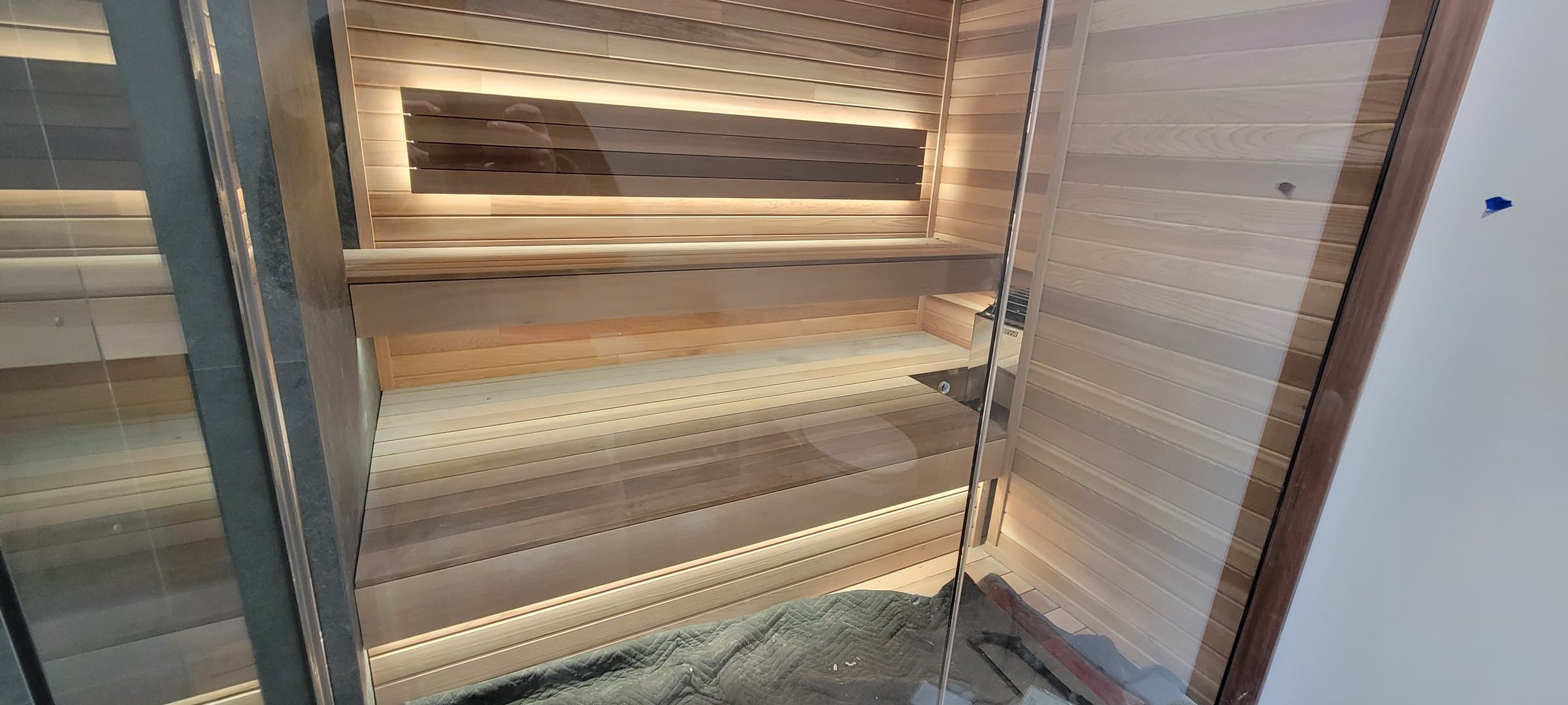 Custom home sauna with tiered cedar slat benches and backlit accent lighting