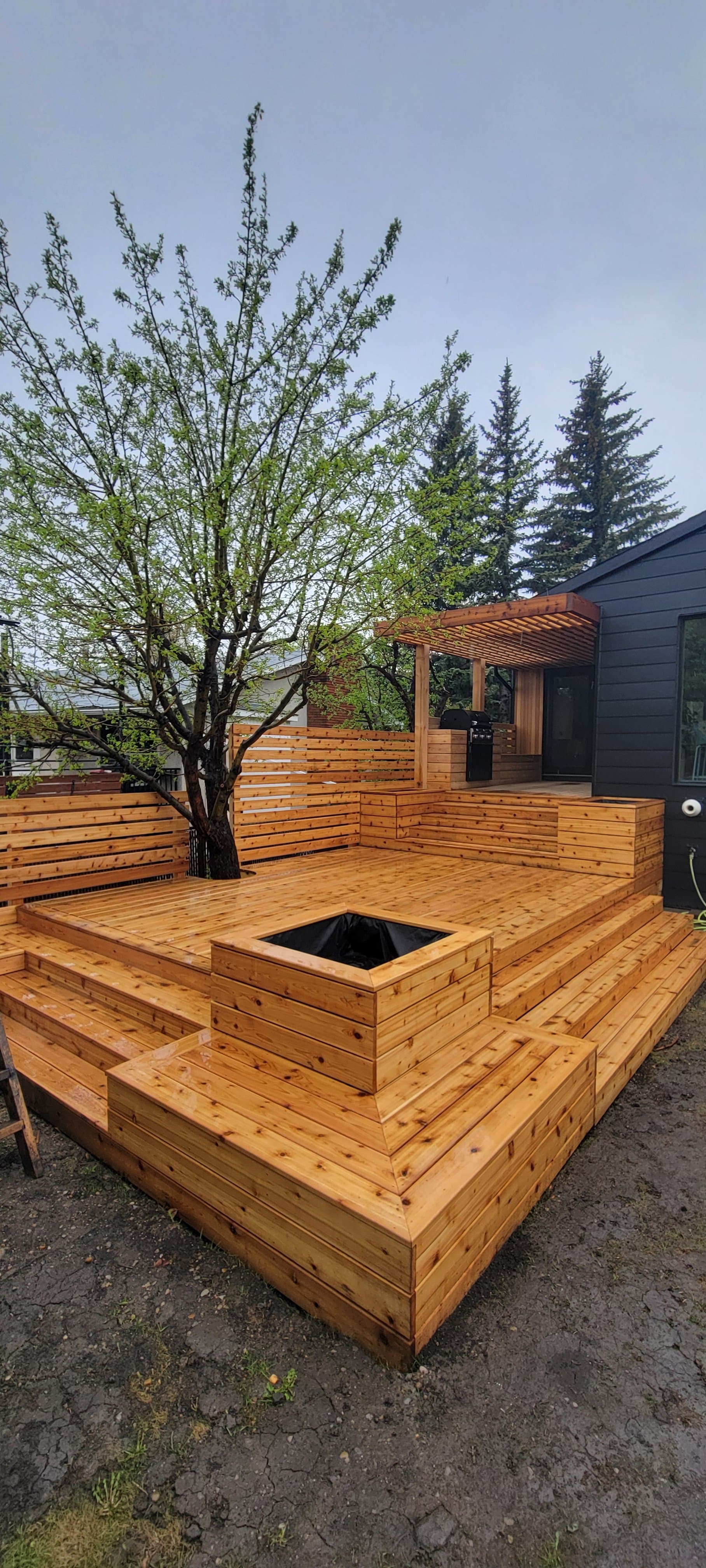 Multi-tier cedar deck with a built-in firepit box, privacy screen, and covered pergola
