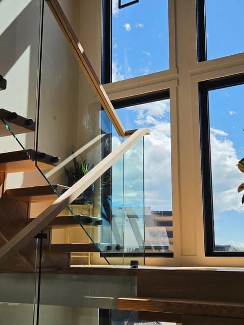 Floating stair treads with glass panel railing and a custom milled red oak handrail