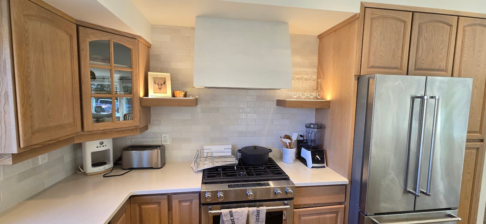 Kitchen with new tile backsplash, plaster range hood surround, and floating wood shelves