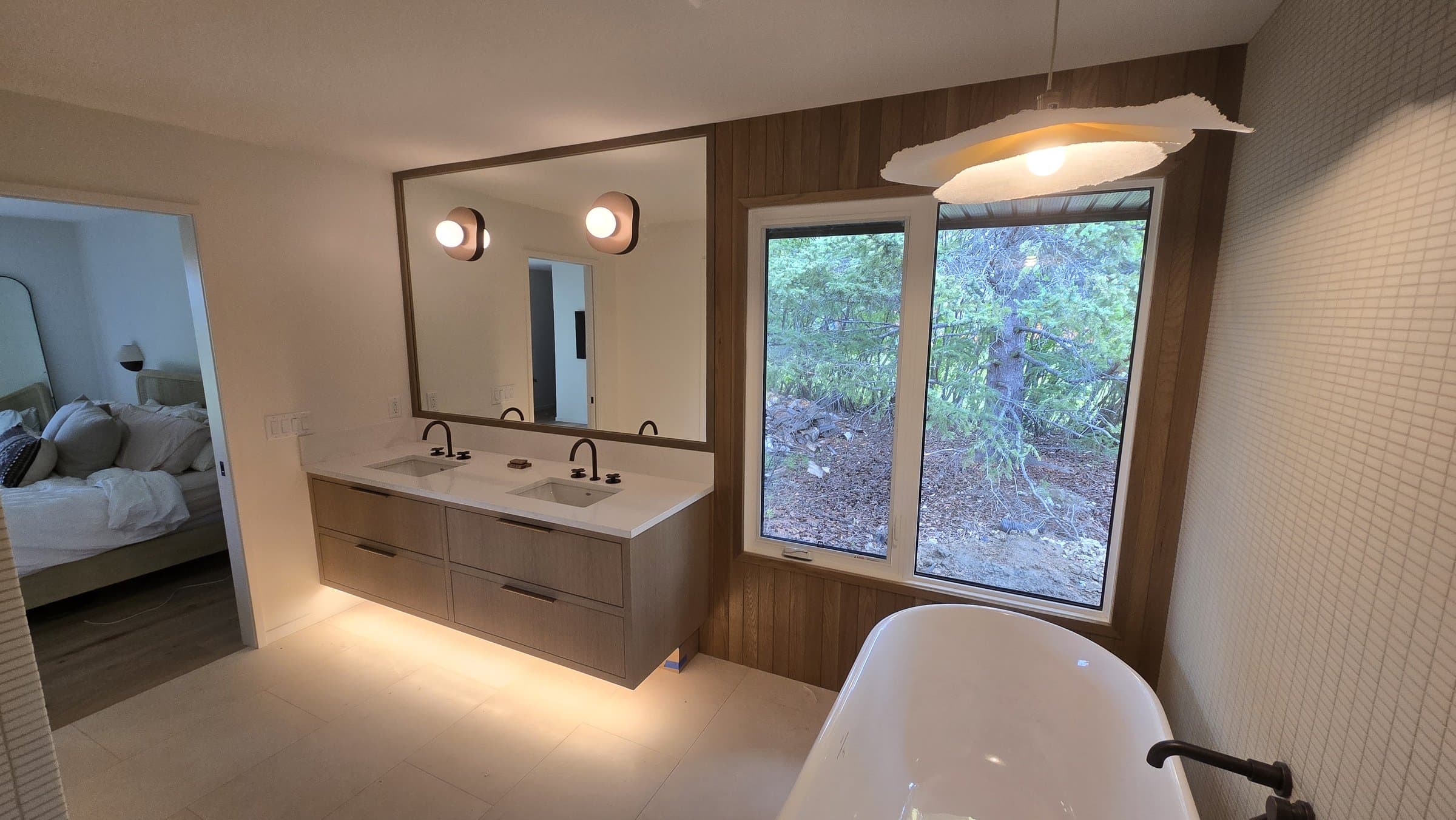 Floating wood double vanity and matching accent wall in a primary ensuite bathroom