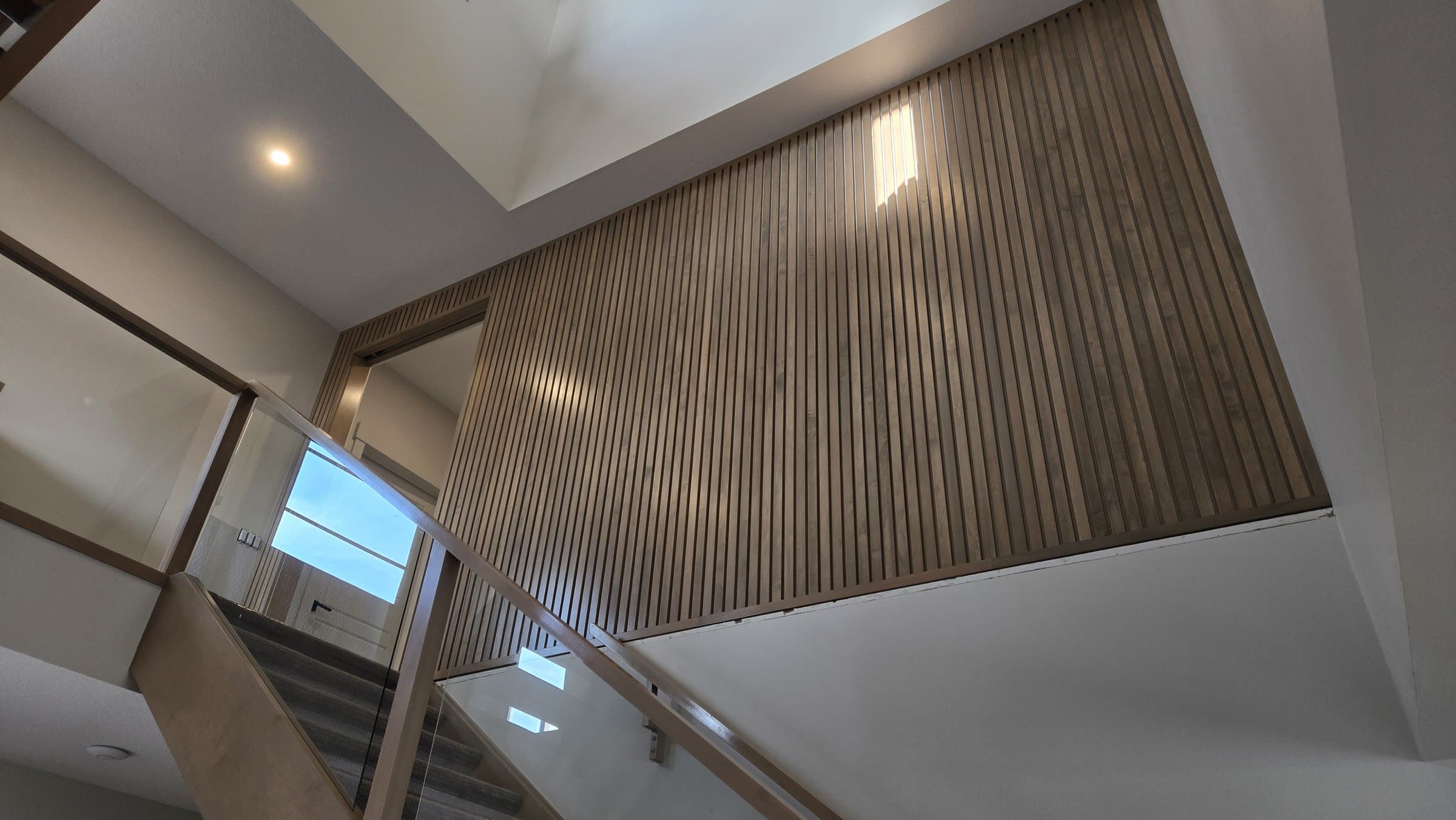 Full-height vertical wood slat accent wall on a stairwell landing above floating stair treads