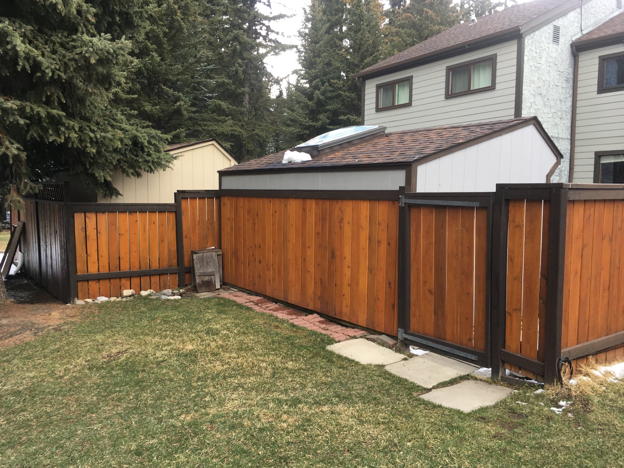 Two-tone cedar privacy fence and matching gate with a dark stained frame